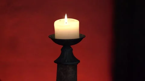 Burning candle. Burning candle in a candlestick on a red background. Stock Footage 279650430