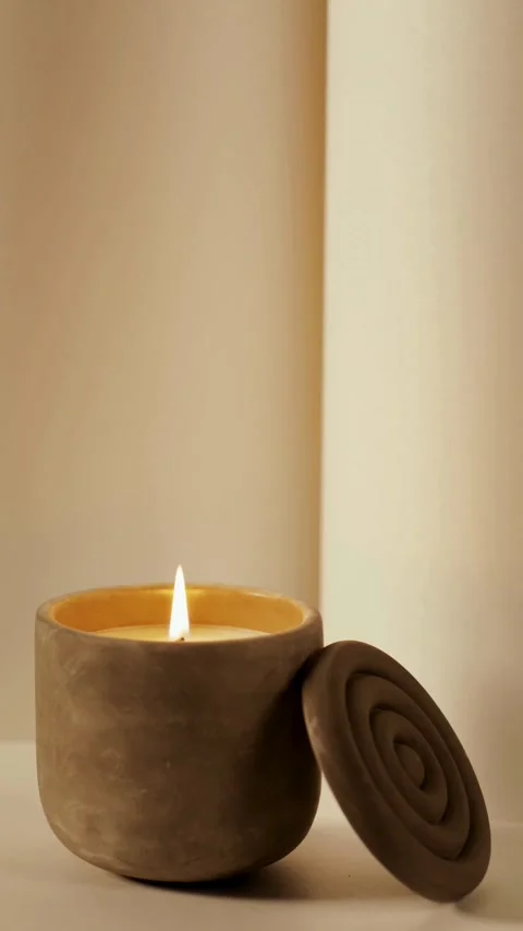 Burning candle in ceramic pot on plain white surface Stock Footage 331774886