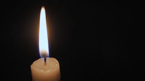 A burning candle close-up in a dark room, the flame from the candle illuminates Video stock 221571649