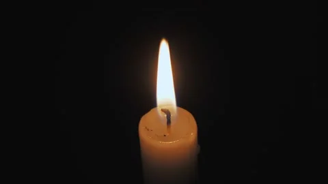 A burning candle close-up in a dark room, the flame from the candle illuminates Video stock 223776475