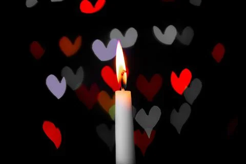 Burning candle on a dark background with light from the lights Stock Photos