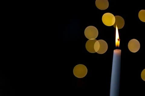 Burning candle on a dark background with light from the lights Stock Photos