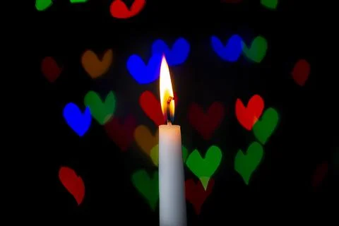 Burning candle on a dark background with light from the lights Stock Photos