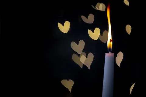 Burning candle on a dark background with light from the lights Stock Photos