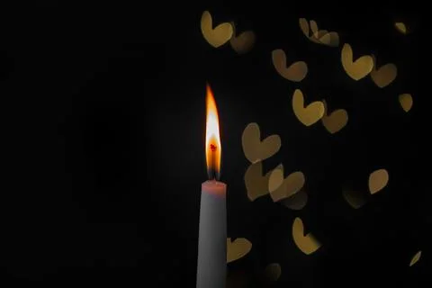 Burning candle on a dark background with light from the lights Stock Photos