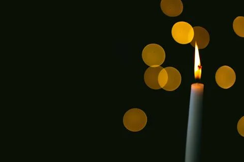 Burning candle on a dark background with light from the lights Stock Photos