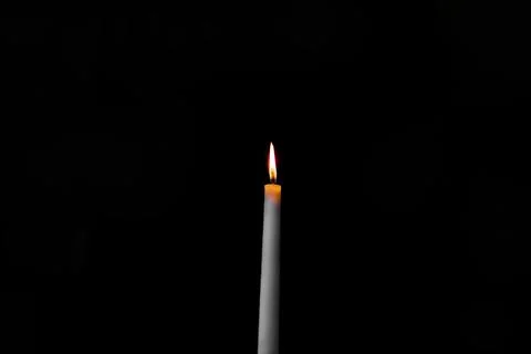 Burning candle on a dark background with light from the lights Stock Photos