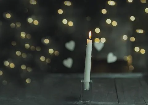 Burning candle on a dark background with light from the lights Stock Photos