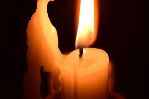 Burning candle on a dark background. Stock Photos