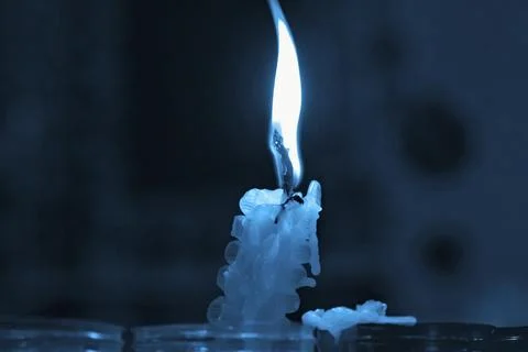 Burning candle on a dark blue background Stock Photos