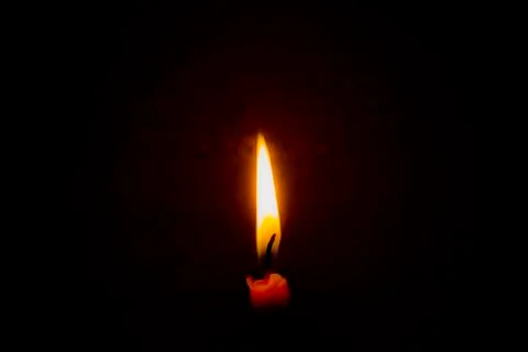 Burning candle in the dark with a dark background. Dark key photo. Stock Photos
