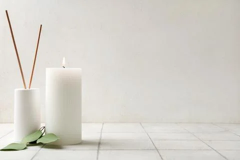 Burning candle with eucalyptus and reed diffuser on white tile table Stock Photos