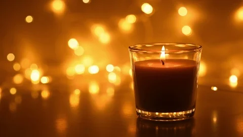 A burning candle flame against blurred bokeh lights at dark background, close Stock Footage 119359855