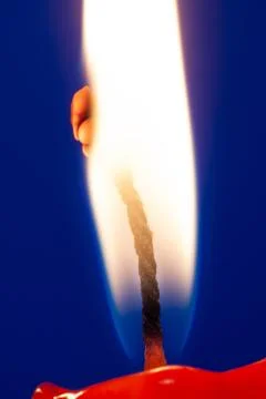 Burning candle flame at blue background Stock Photos