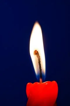 Burning candle flame at blue background Stock Photos
