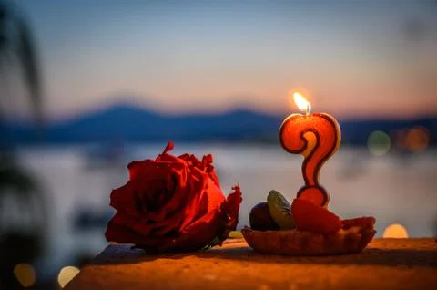 Burning candle in the form of a question mark and a rose close up selective Foto stock