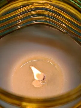 Burning candle glowing inside patterned glass holder Stockfoto's