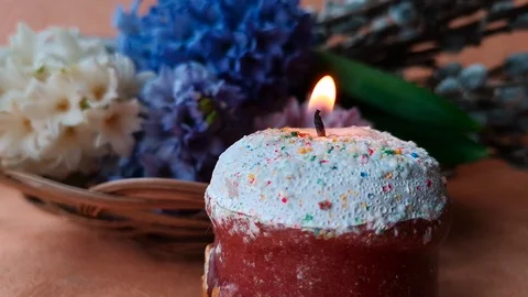 Burning candle made in the shape of Easter cake, flowers Stock Footage 104849678