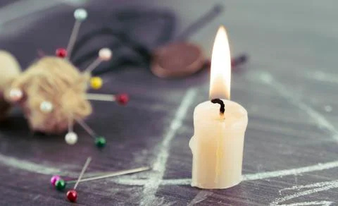 A burning candle on a magic circle next to occult needles. Foto stock