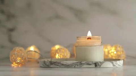 Burning candle on marble tray with warm lights on a beige background, autum.. Stock Footage 253576178