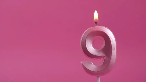 Burning candle with number 9 on a pink background. Copy space. place for text. Stock Footage 274676423