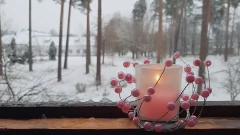 Burning candle with pink bead decor on wooden windowsill Stock Footage 323112398