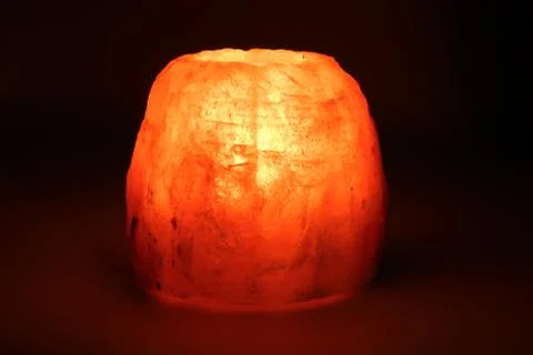 Burning candle placed in a candlestick made of a piece of salt Stock Photos