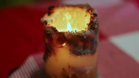 A burning candle stands on a red table for Valentine's Day Video stock 230292142