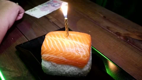A burning candle is stuck into a large sushi Stock Footage 285252155