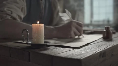 Burning candle on a table against the blurred background of an inventor drawing Video stock 337649418