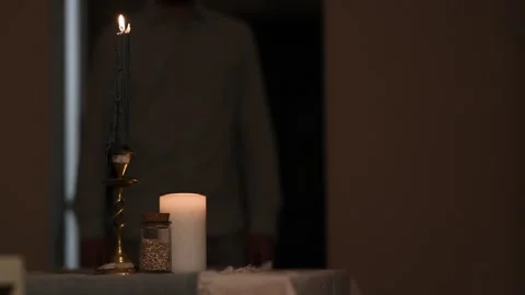 Burning candle on table as man walks by in blurred background quietly. 库存影片 309259609