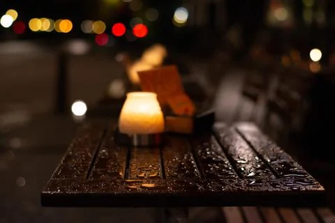 Burning candle on a wet wooden table after rain. Stock Photos