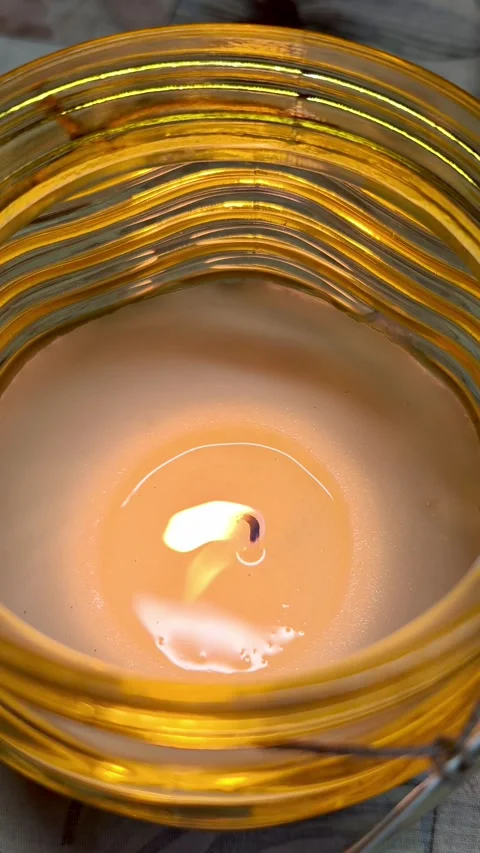 Burning candle wick flame flickering in yellow glass jar Stock Footage 339322739