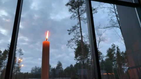 Burning candle by window against evening forest sky Stock Footage 319802258