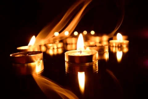 Burning candles on a dark background with reflection. Stock Photos