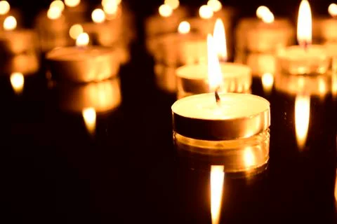 Burning candles on a dark background with reflection. Stock Photos