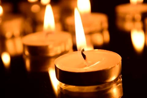 Burning candles on a dark background with reflection. Stock Photos