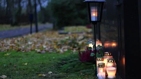 Burning candles placed on graves in a quiet cemetery, 4K ultra HD. Video stock 320642239