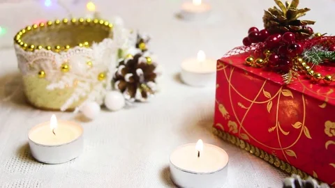 Burning candles, a red gift box and decorative ornaments with shimmering Video stock 82407562