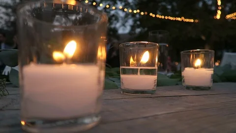 Burning candles sit on an outdoor ￼table￼ for the evenings event￼￼. Stock Footage 119077067