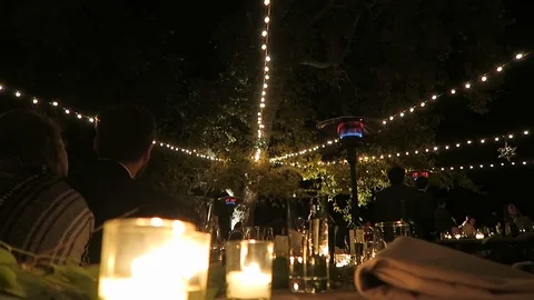 Burning candles sit on an outdoor ￼table￼ for the evenings event￼￼. Stock Footage 119078432