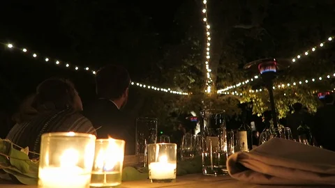 Burning candles sit on an outdoor ￼table￼ for the evenings event￼￼. Stock Footage 119078593
