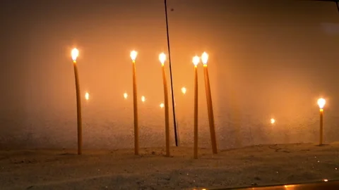 Burning candles standing at sand inside place for candles. Stock Footage 155117319