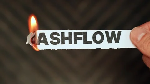 Burning “cashflow” label held by hand, symbolizing cash flow problems, income Stock Footage 333655897