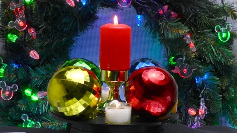 A burning Christmas candle surrounded by colored checkered balls Stock Footage 164798936