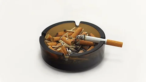 Burning Cigarette on Ashtray full of ashes and buds -White Background -Time laps Stock Footage 123009323