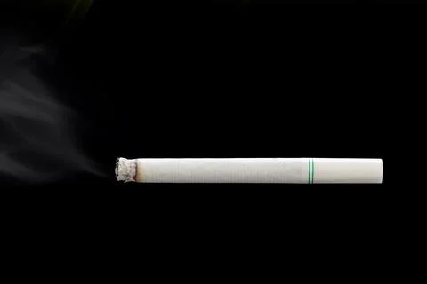 Burning cigarette on black background. Stock Photos