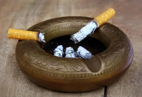 Burning cigarette on an old ashtray Stock Photos