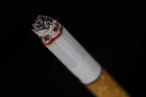 Burning cigarette with smoke on black background Foto stock