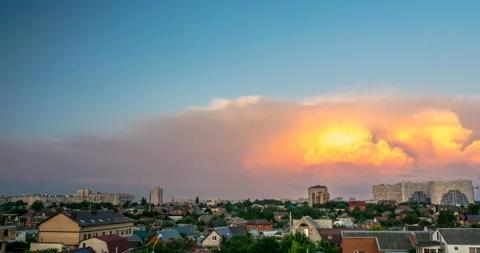 Burning clouds at sunset are flying against the backdrop of the cityscape Stock Footage 111424851
